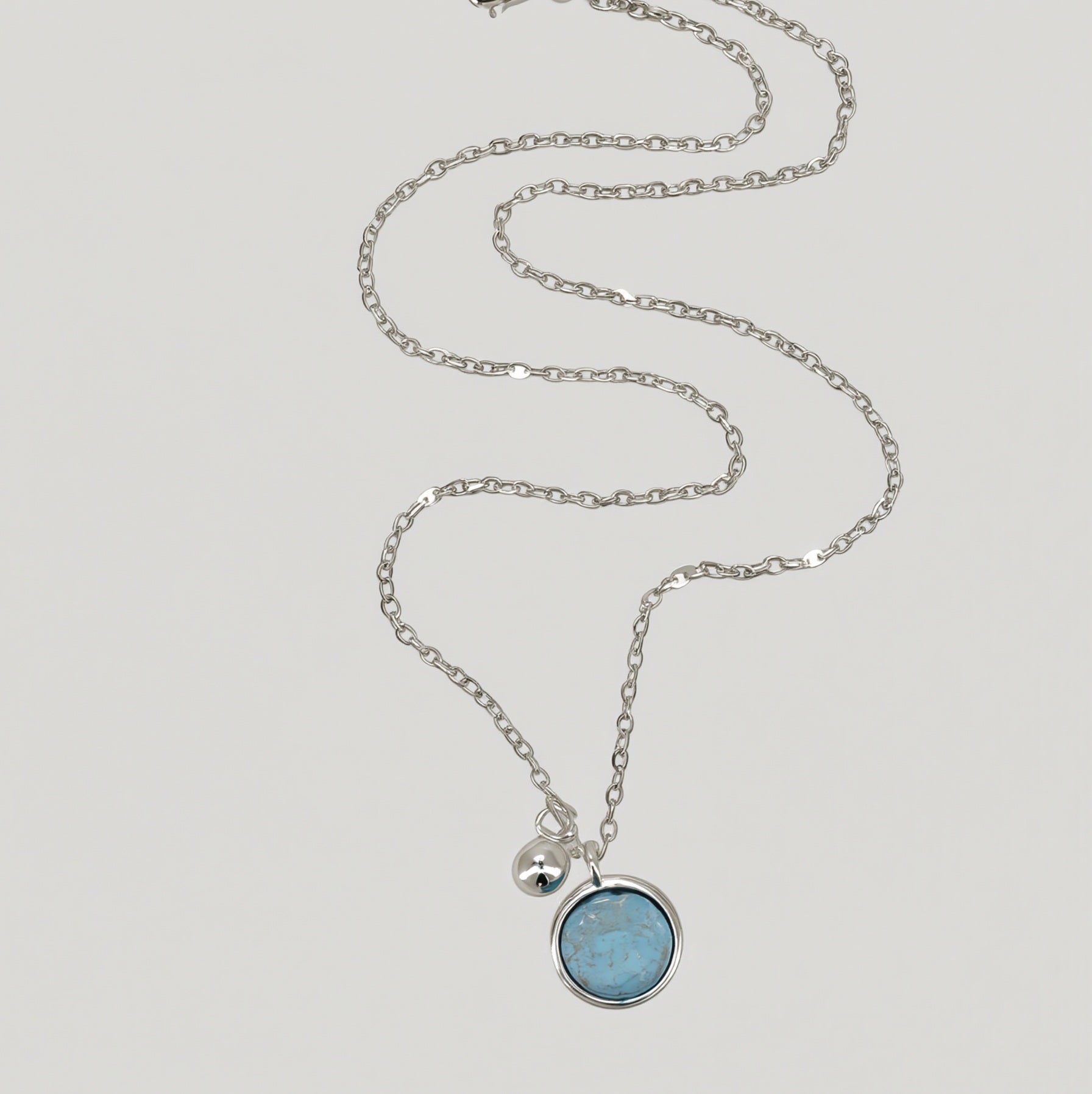 Amara Jewels sterling silver necklace with a round aqua charm and a polished silver bead.