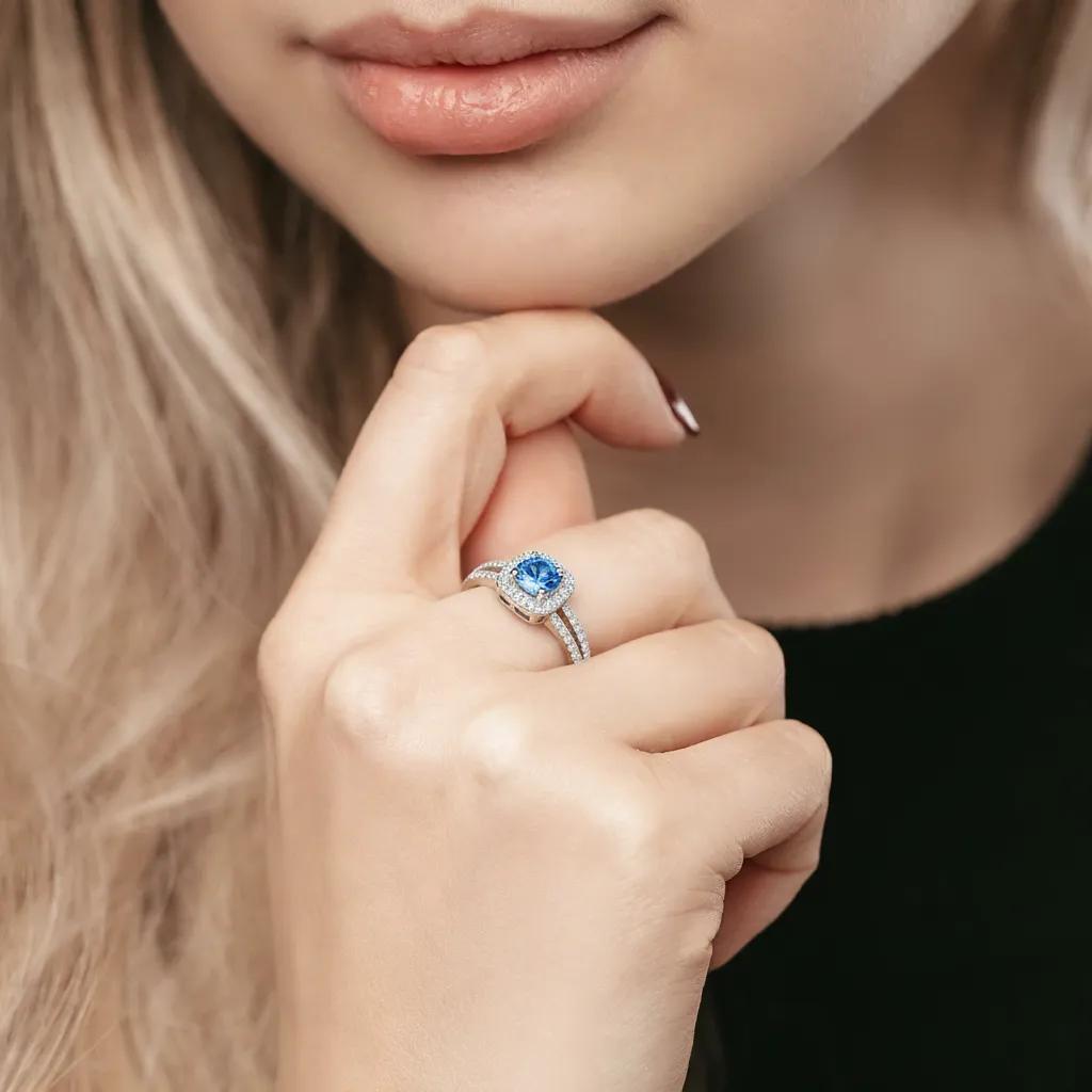 Amara Jewels 925 sterling silver ring with a central blue cubic zirconia surrounded by a halo of small clear stones. Split shank design.