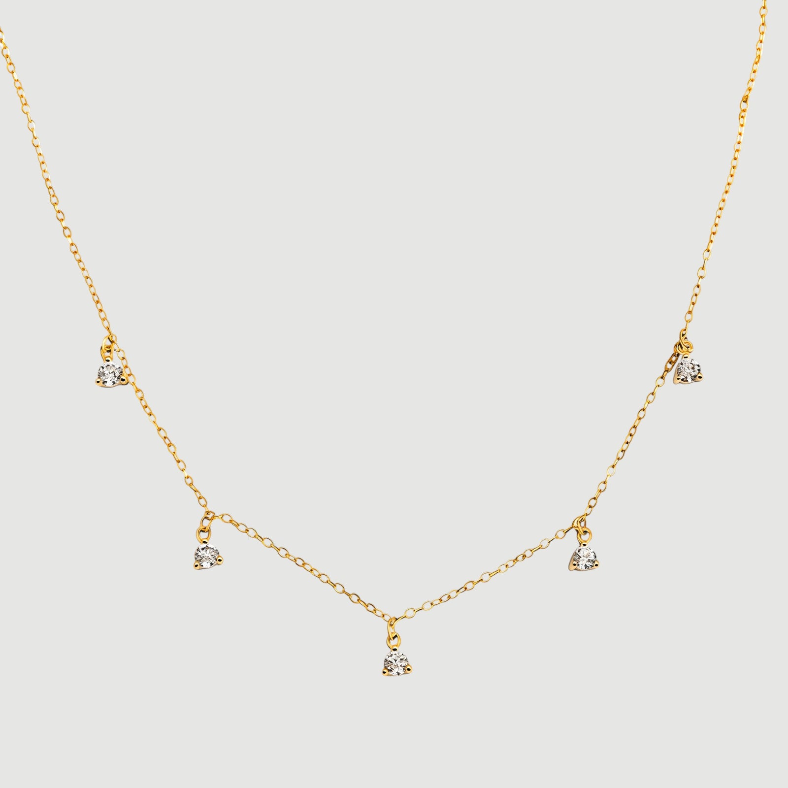 Amara Jewels gold-plated sterling silver necklace with five small crystal pendants spaced along a delicate chain.