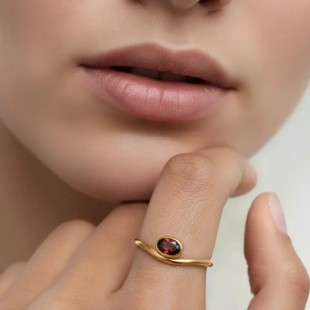 Amara Jewels 18K gold vermeil sterling silver ring with a bezel-set oval garnet gemstone. Minimalist design.