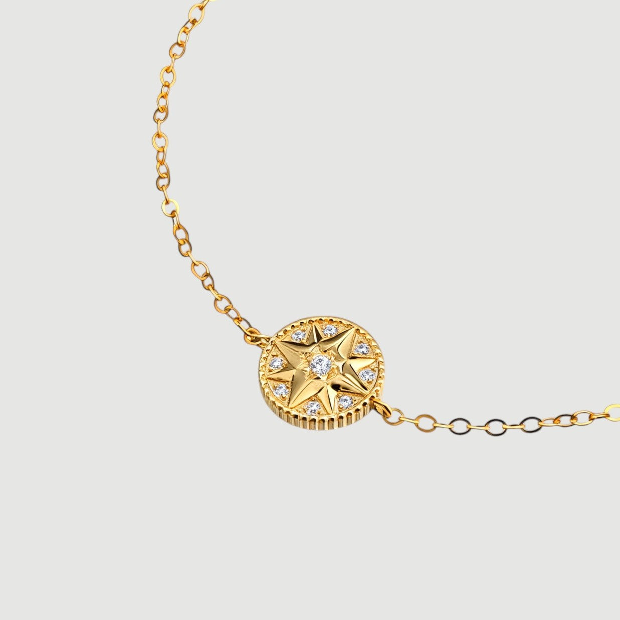 Amara Jewels gold-plated sterling silver bracelet with a celestial compass charm adorned with cubic zirconia. Adjustable chain.
