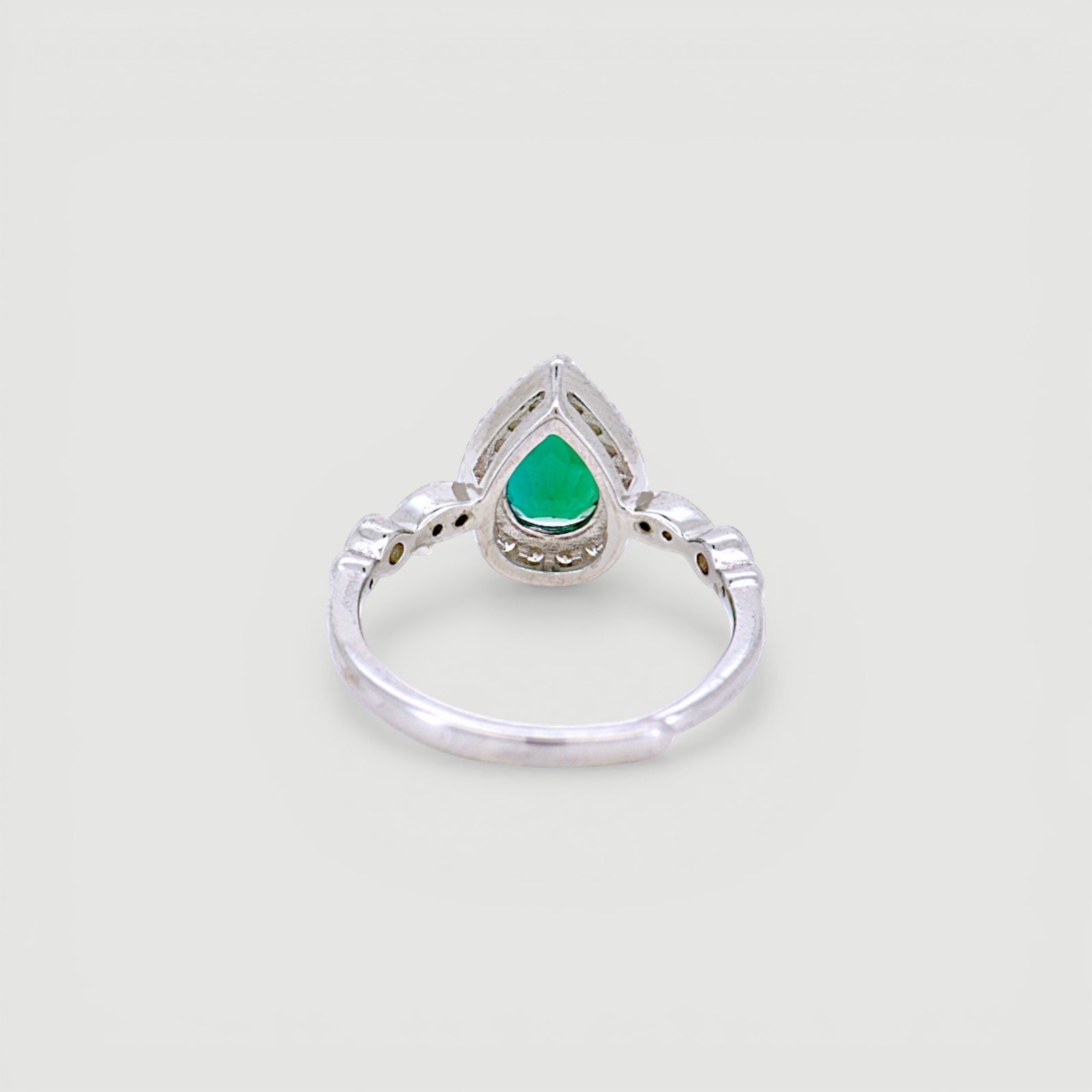 Amara Jewels sterling silver ring with a green teardrop gemstone surrounded by small clear stones. Intricate detailing on band.