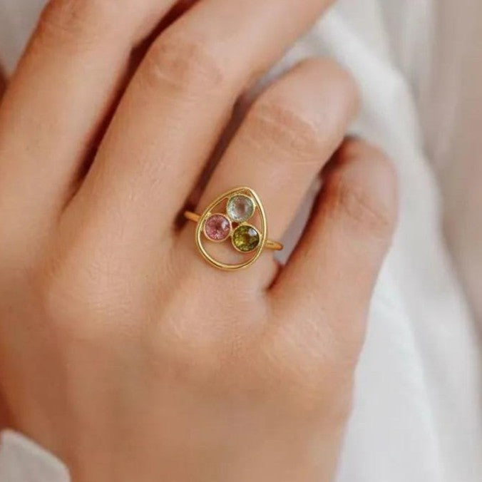 Amara Jewels gold vermeil ring with bezel-set pink, green, and black tourmaline gemstones in a sculptural open frame.