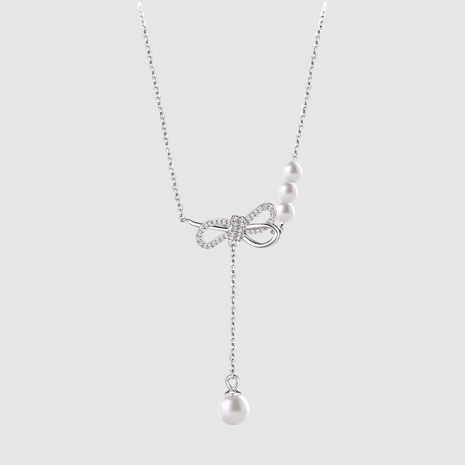 Amara Jewels sterling silver necklace with cubic zirconia bow and trio of white pearls and dangling single pearl drop.
