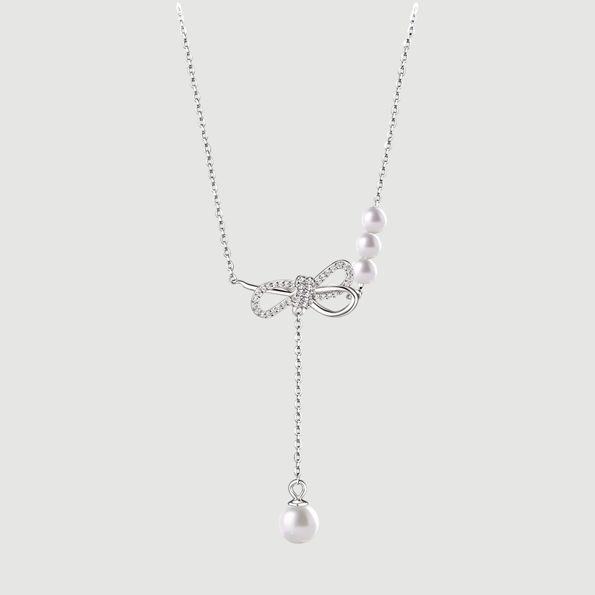 Amara Jewels sterling silver necklace with cubic zirconia bow and trio of white pearls and dangling single pearl drop.