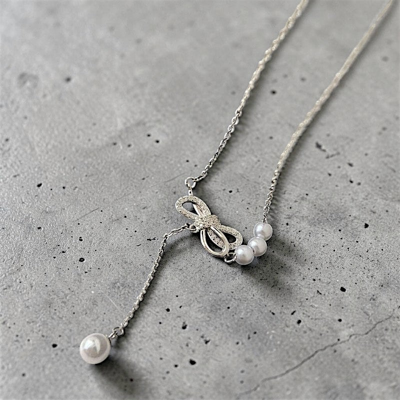 Amara Jewels sterling silver necklace with cubic zirconia bow and white pearls, featuring a single pearl drop.