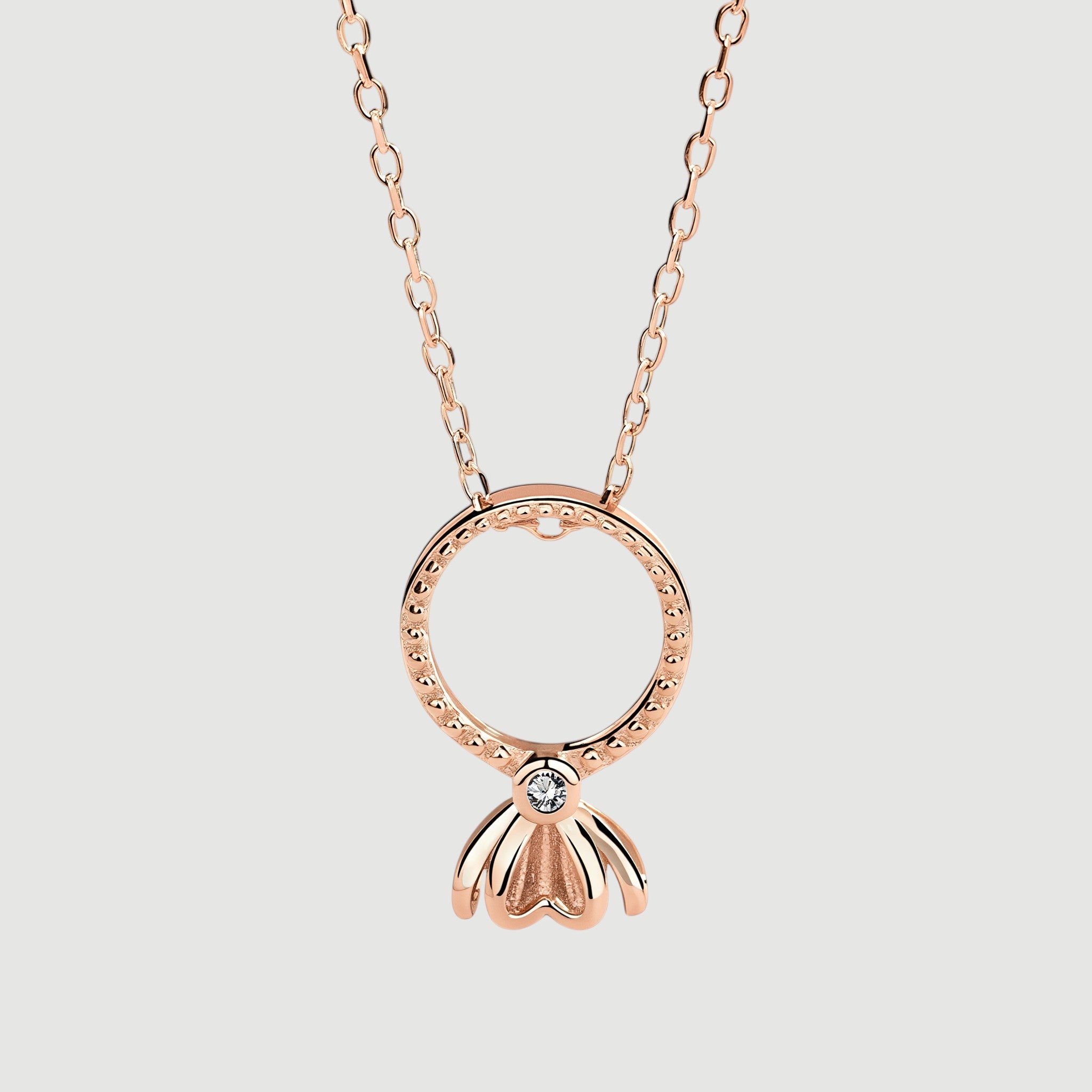 Amara Jewels rose gold plated sterling silver necklace with open circle pendant and flower drop charm with center stone.