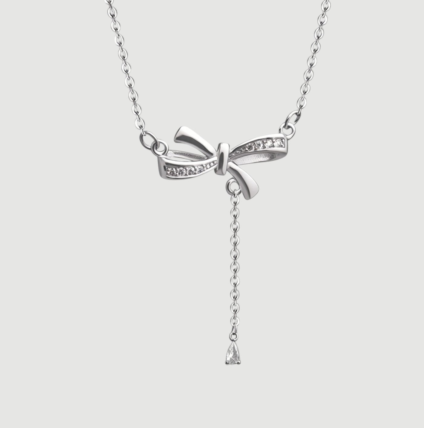 Amara Jewels sterling silver bow pendant necklace with cubic zirconia accents and a dangling pear-shaped stone.