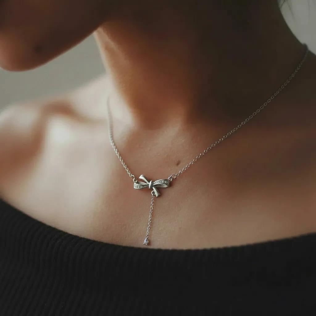 Amara Jewels sterling silver bow pendant necklace with cubic zirconia accents and a dangling pear-shaped stone.