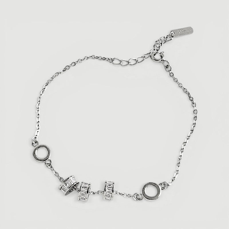 Amara Jewels 925 sterling silver bracelet with geometric charms and adjustable chain. Features circular and bar charms with baguette-cut stones.