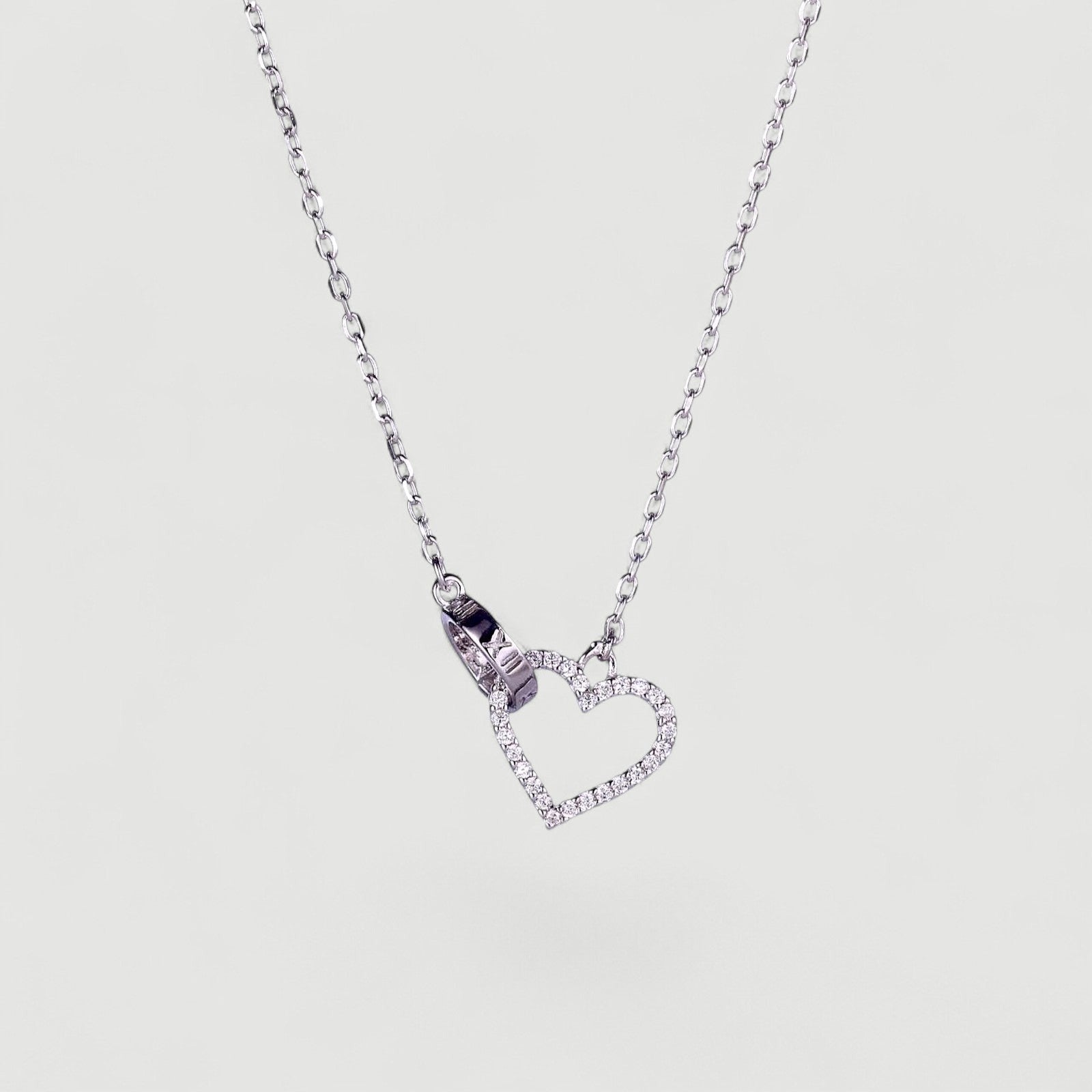 Amara Jewels sterling silver necklace with a linked open heart pendant adorned with cubic zirconia and a circle charm with Roman numerals.