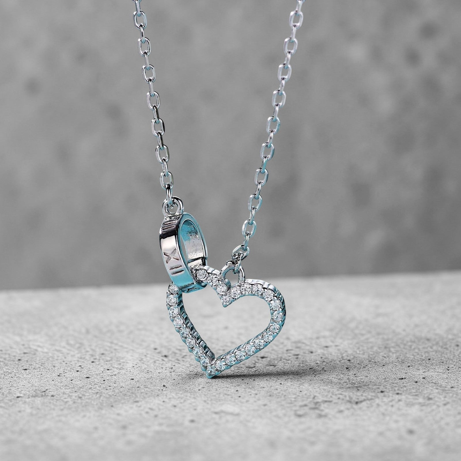 Amara Jewels sterling silver necklace with a linked open heart pendant adorned with cubic zirconia and a circle charm with Roman numerals.