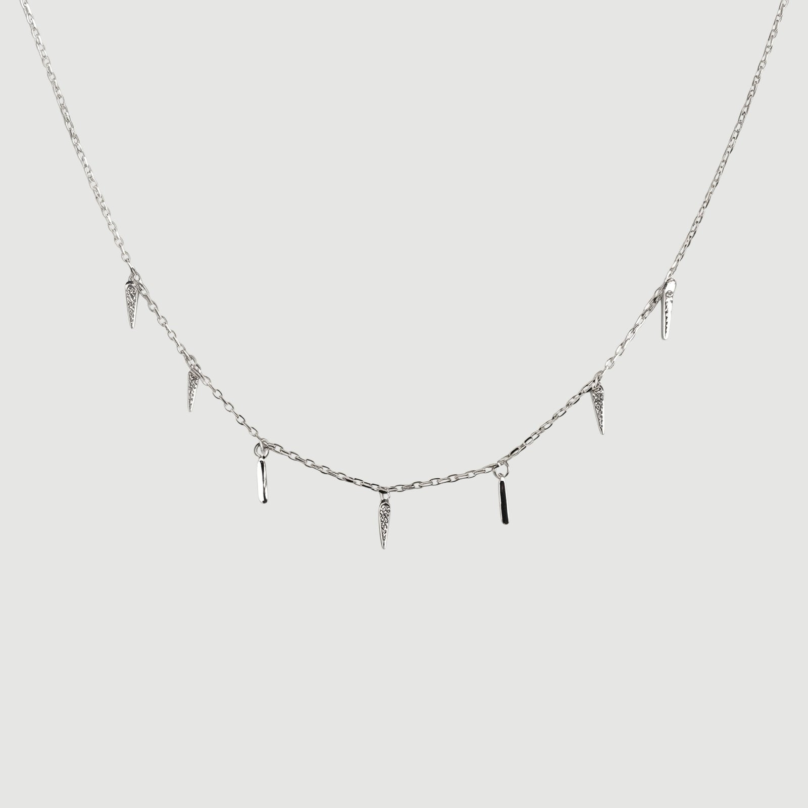 Amara Jewels rhodium-plated sterling silver necklace with dangling spike charms and clear crystals.