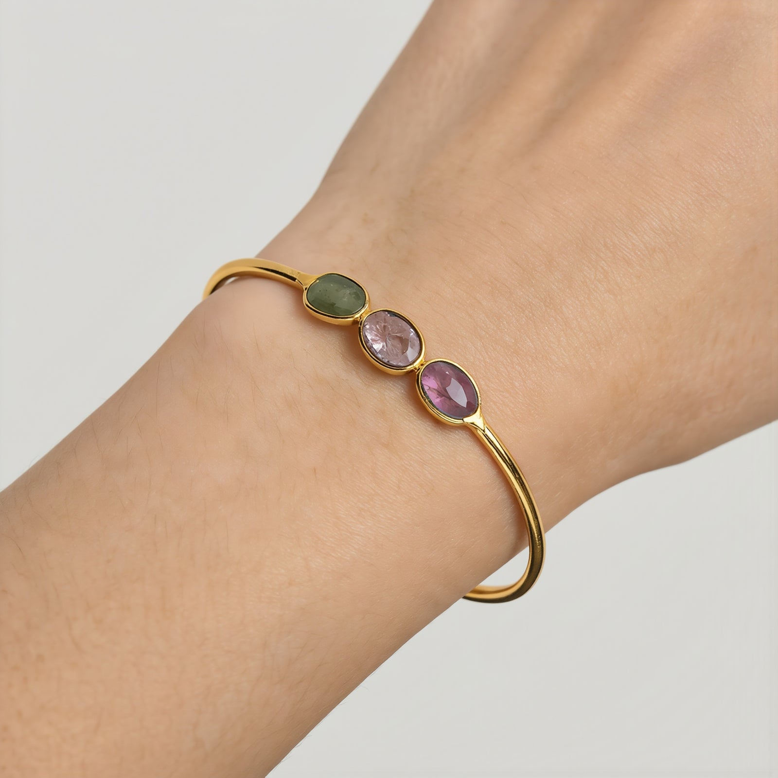 Amara Jewels 18K gold vermeil wrap bracelet with three bezel-set oval tourmaline gemstones in pink, green, and red.