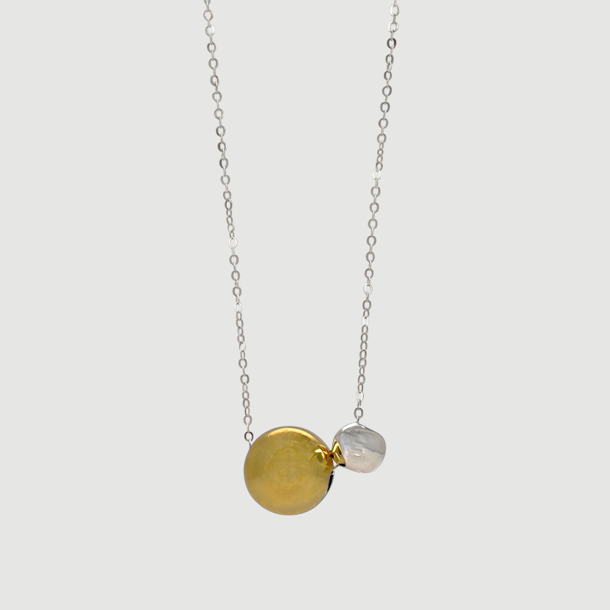 Amara Jewels two-tone sphere pendant necklace with polished silver chain, featuring a large gold sphere and a smaller silver sphere.
