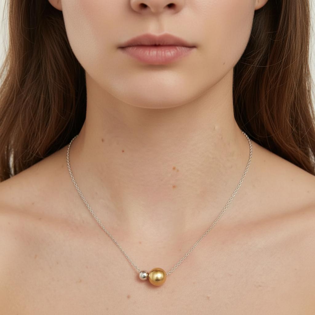 Amara Jewels two-tone sphere pendant necklace with polished silver chain, featuring a large gold sphere and a smaller silver sphere.
