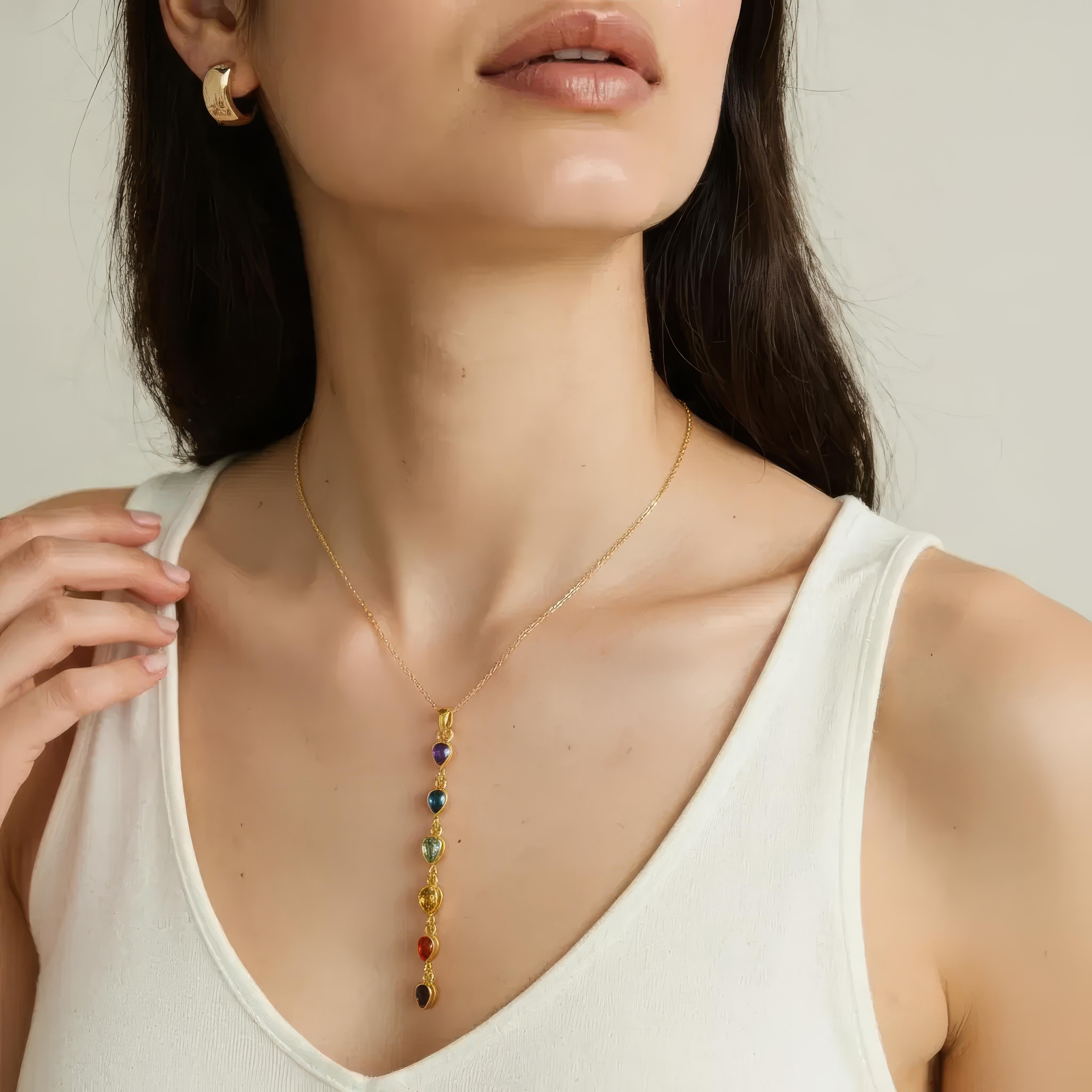 Woman wearing a gold necklace with colorful beads against a neutral background