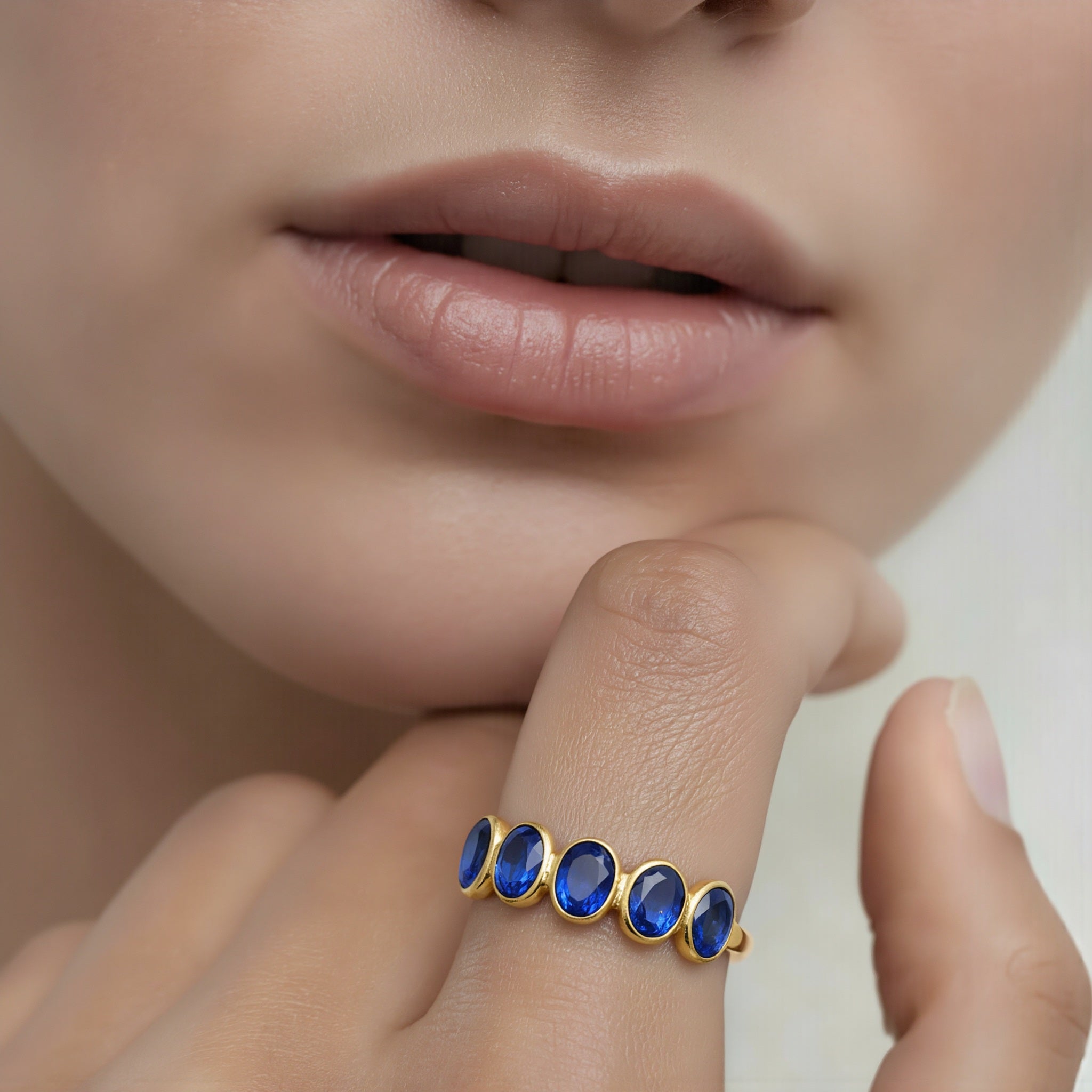 Amara Jewels gold-plated sterling silver band ring with five oval-cut blue sapphire gemstones.