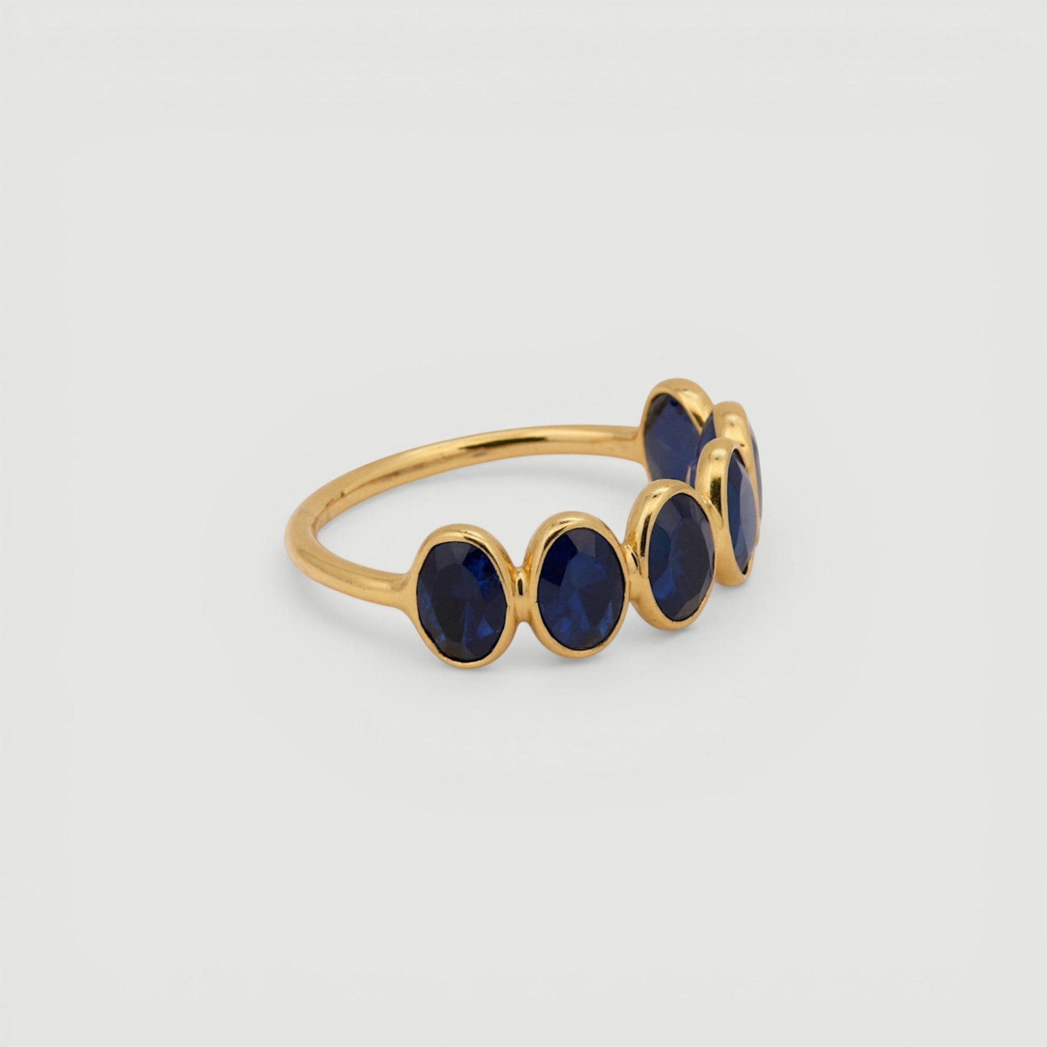 Amara Jewels gold-plated sterling silver band ring with five oval-cut blue sapphire gemstones.