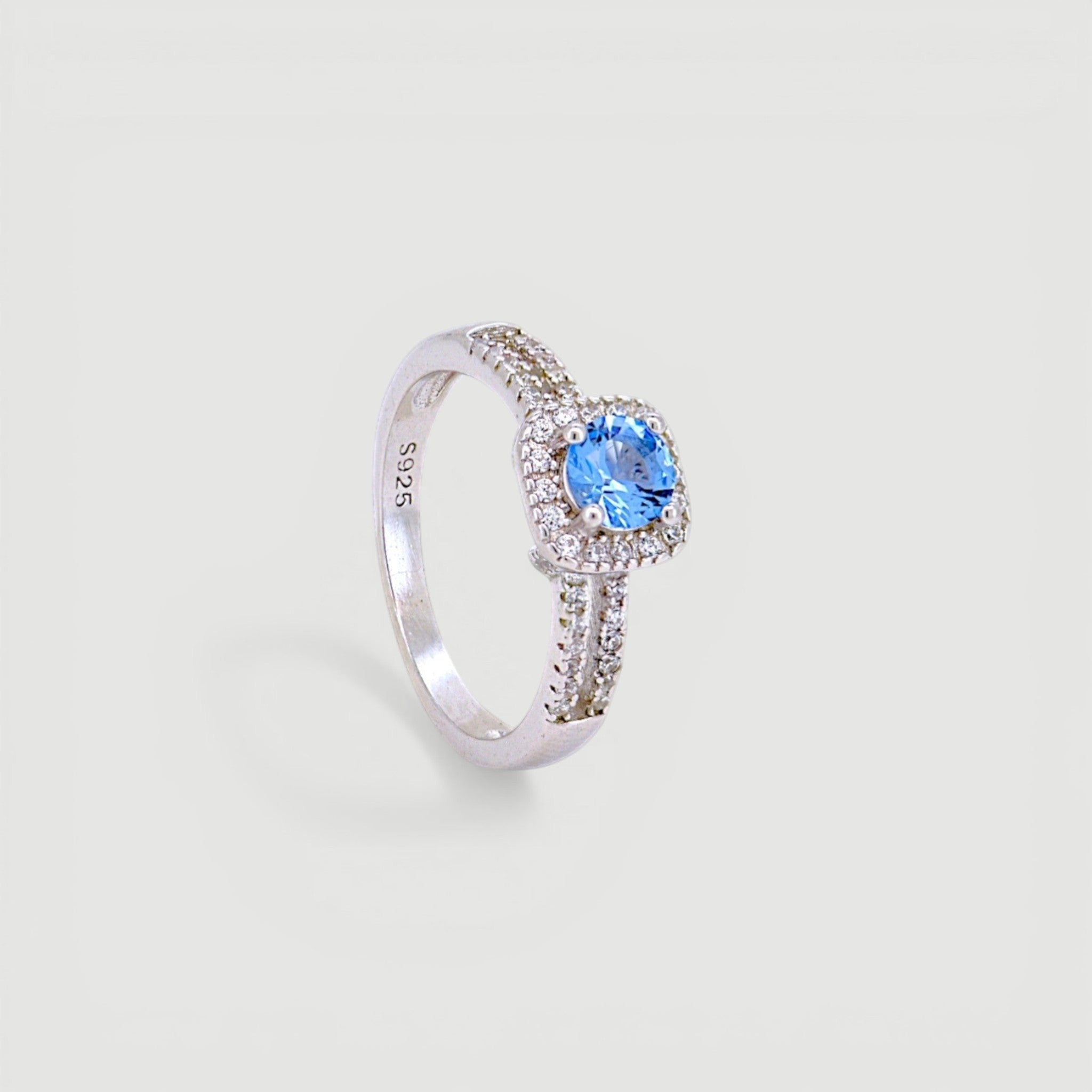 Amara Jewels 925 sterling silver ring with a central blue cubic zirconia surrounded by a halo of small clear stones. Split shank design.