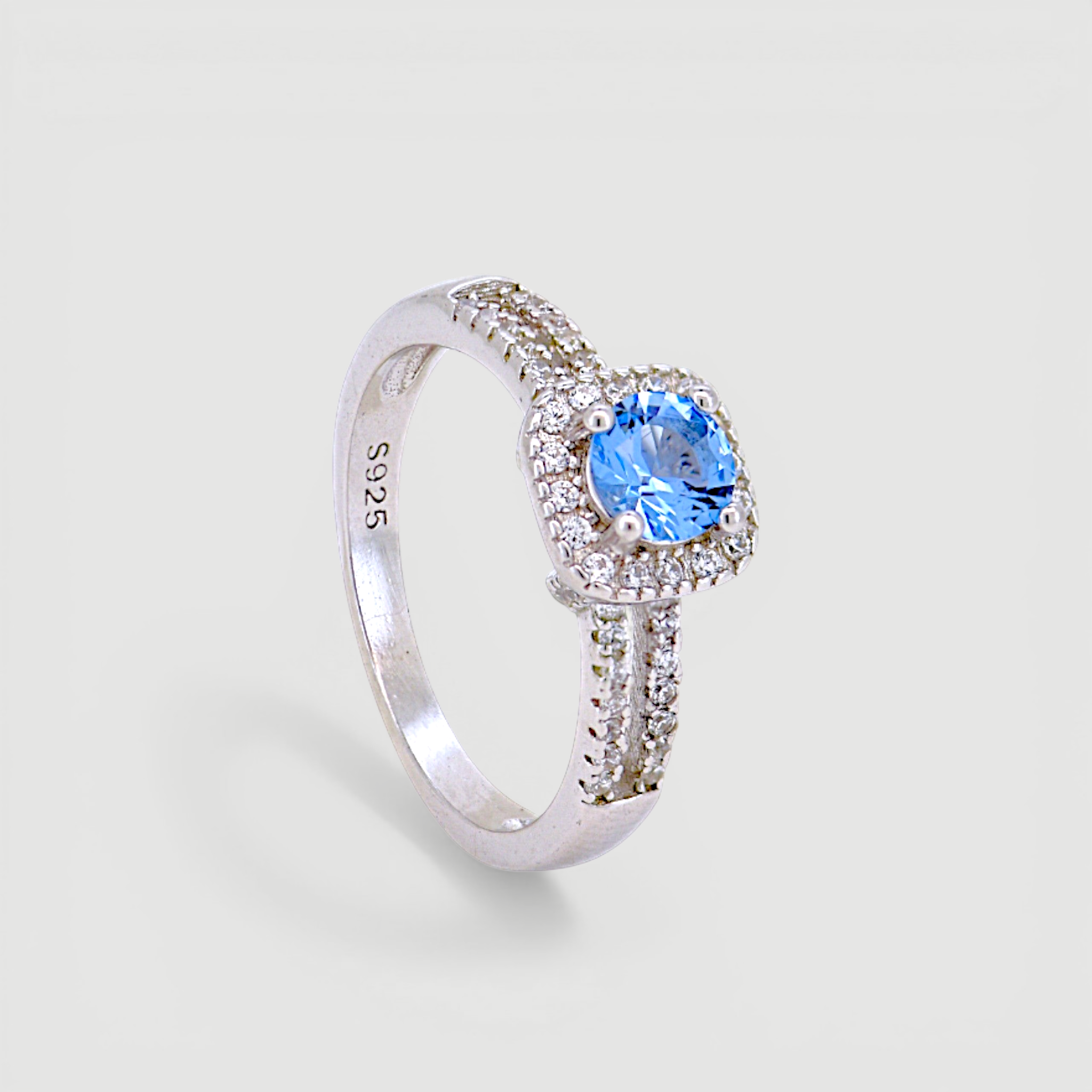 Amara Jewels 925 sterling silver ring with a central blue cubic zirconia surrounded by a halo of small clear stones. Split shank design.