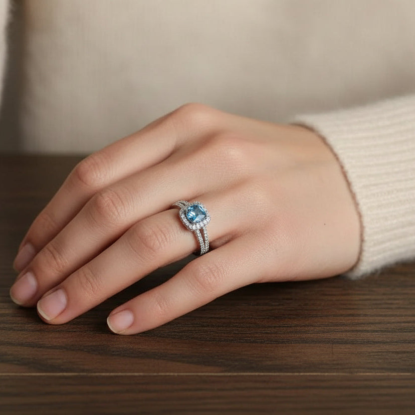 Amara Jewels 925 sterling silver ring with a central blue cubic zirconia surrounded by a halo of small clear stones. Split shank design.