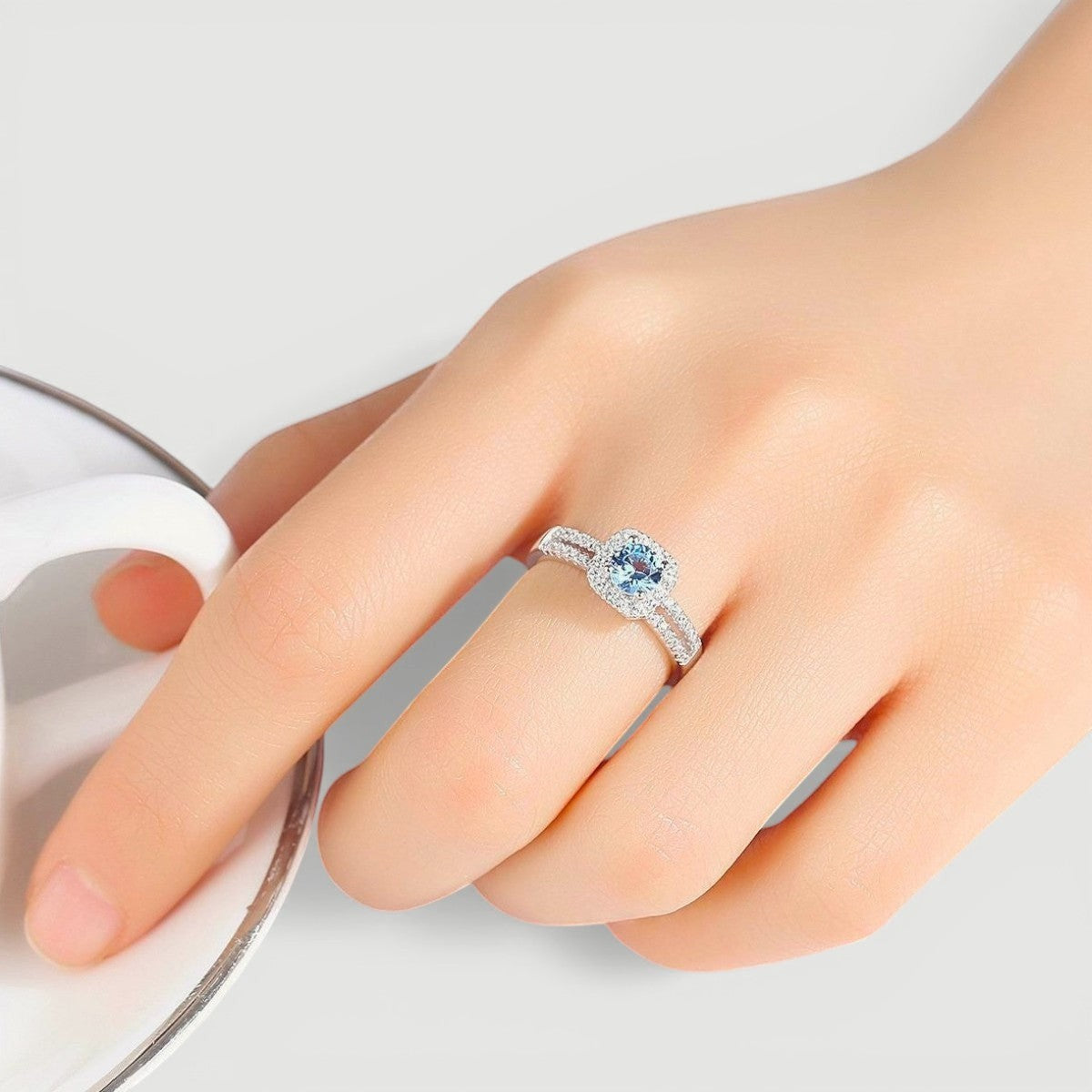 Amara Jewels 925 sterling silver ring with a central blue cubic zirconia surrounded by a halo of small clear stones. Split shank design.