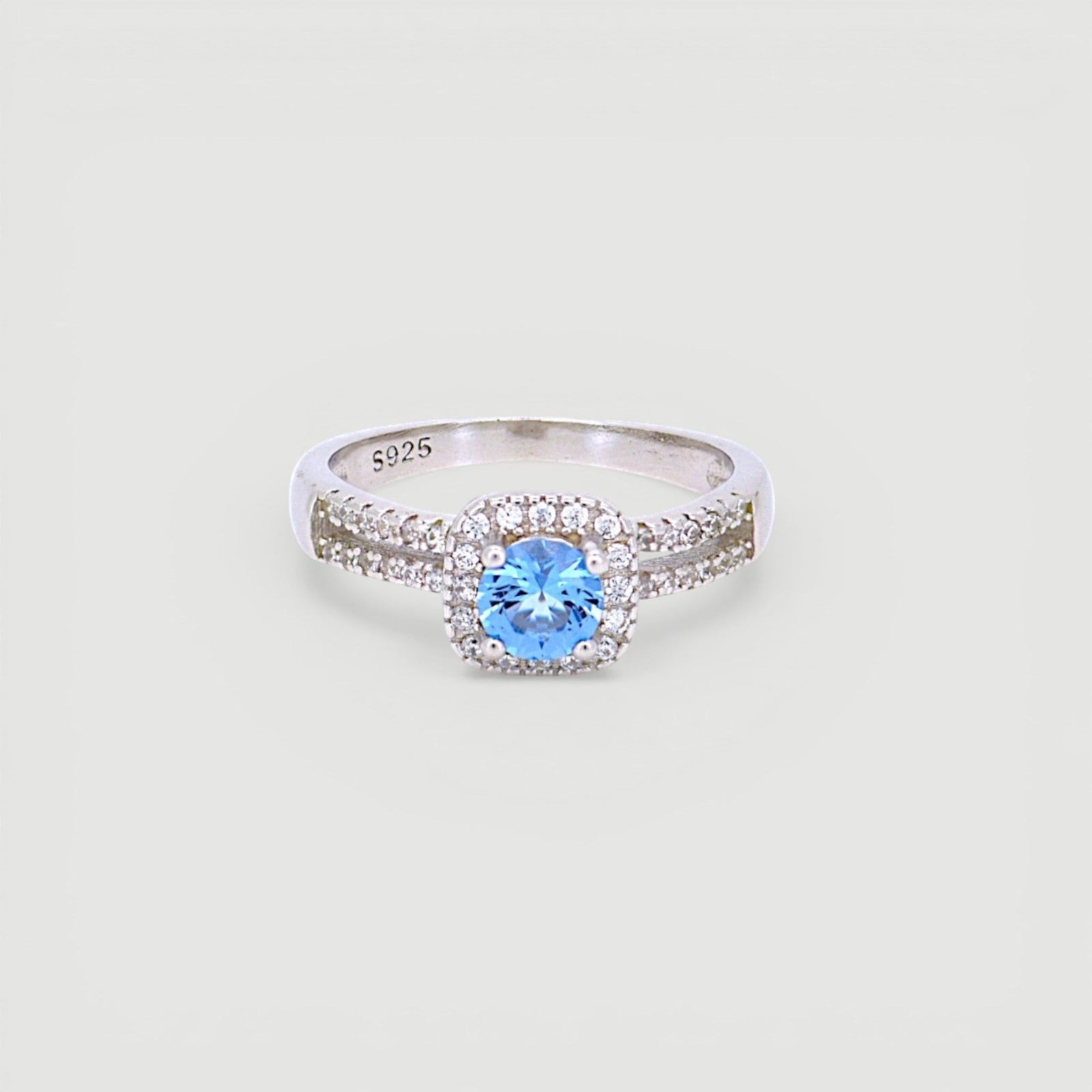 Amara Jewels 925 sterling silver ring with a central blue cubic zirconia surrounded by a halo of small clear stones. Split shank design.