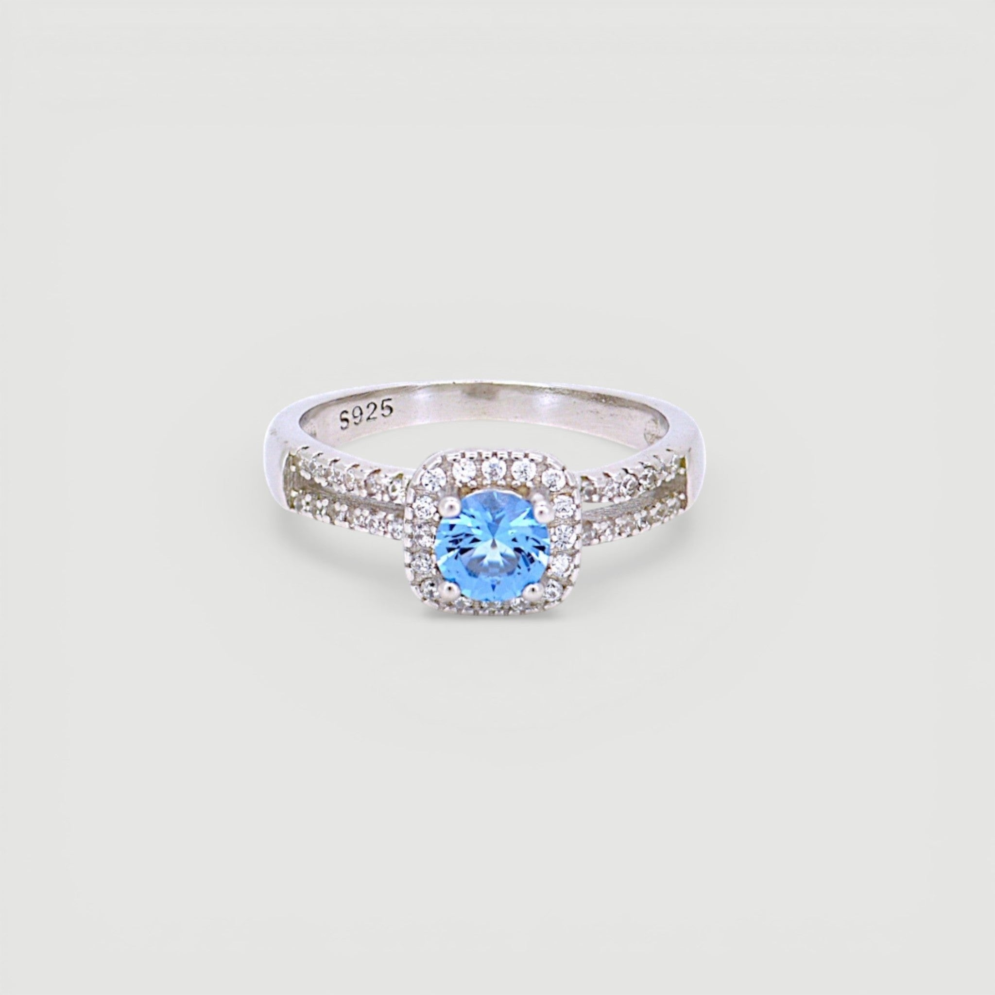 Amara Jewels 925 sterling silver ring with a central blue cubic zirconia surrounded by a halo of small clear stones. Split shank design.