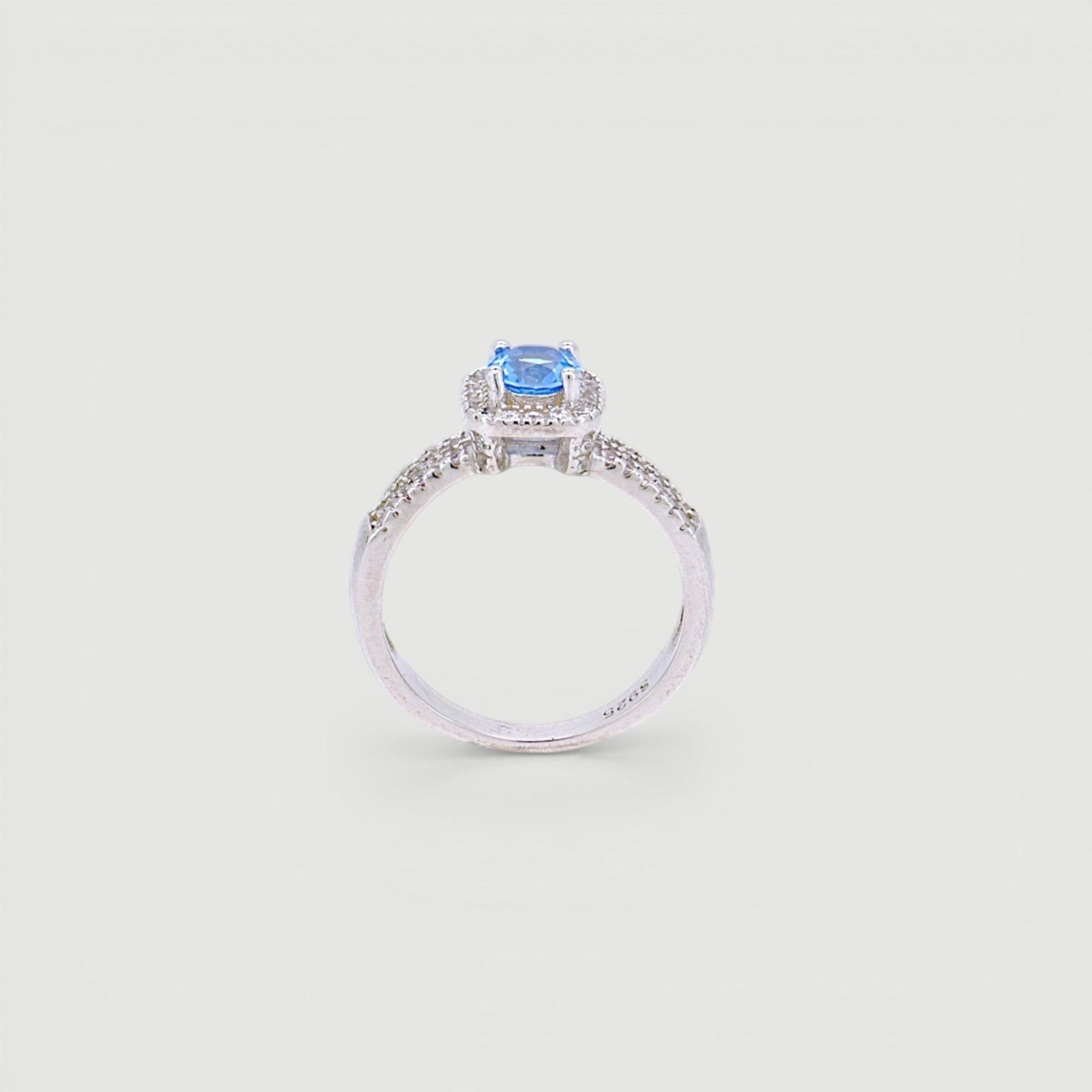 Amara Jewels 925 sterling silver ring with a central blue cubic zirconia surrounded by a halo of small clear stones. Split shank design.