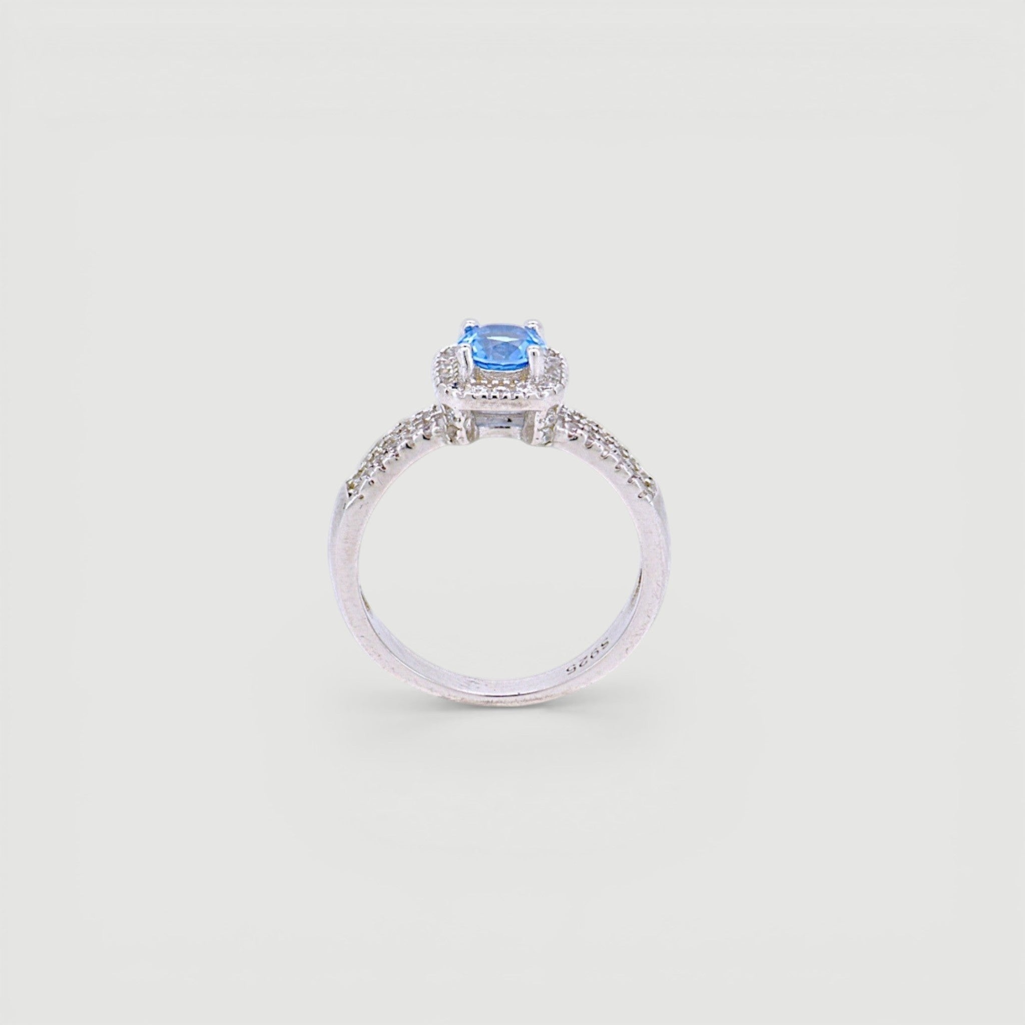 Amara Jewels 925 sterling silver ring with a central blue cubic zirconia surrounded by a halo of small clear stones. Split shank design.