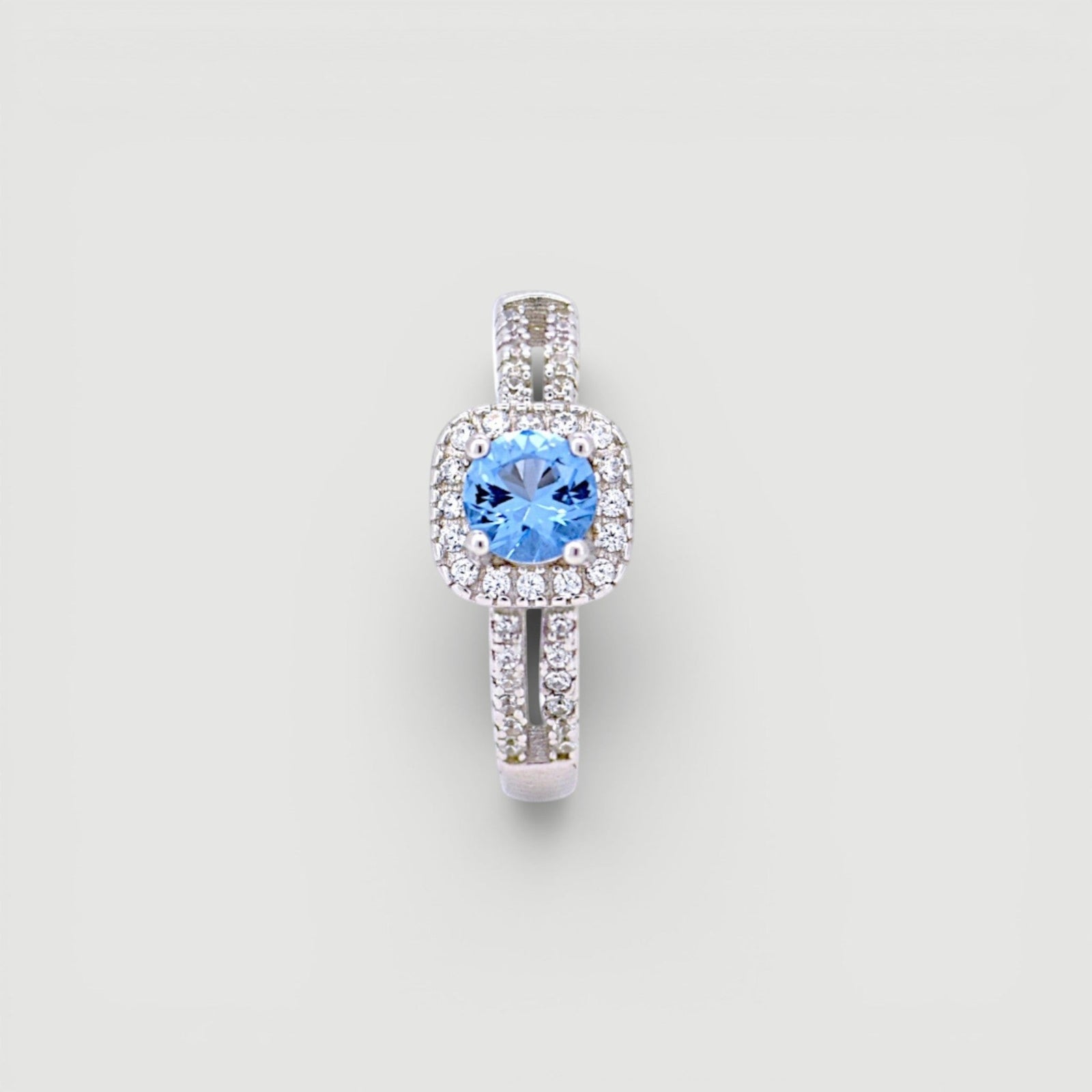 Amara Jewels 925 sterling silver ring with a central blue cubic zirconia surrounded by a halo of small clear stones. Split shank design.