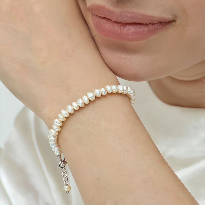 Amara Jewels white freshwater pearl bracelet with a silver clasp and extender chain, worn on a woman's wrist.