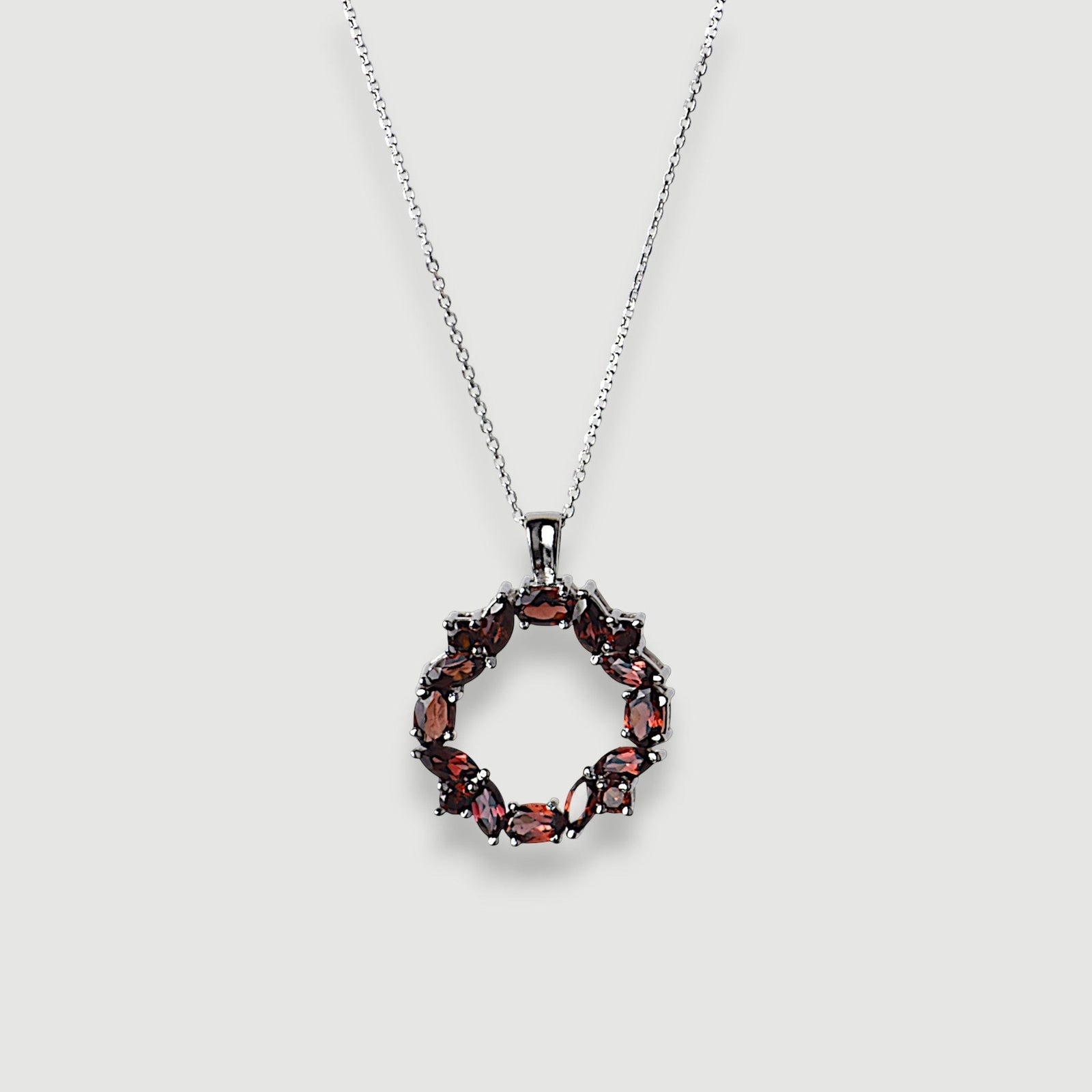 Amara Jewels sterling silver necklace with a wreath pendant featuring deep red natural garnet gemstones.