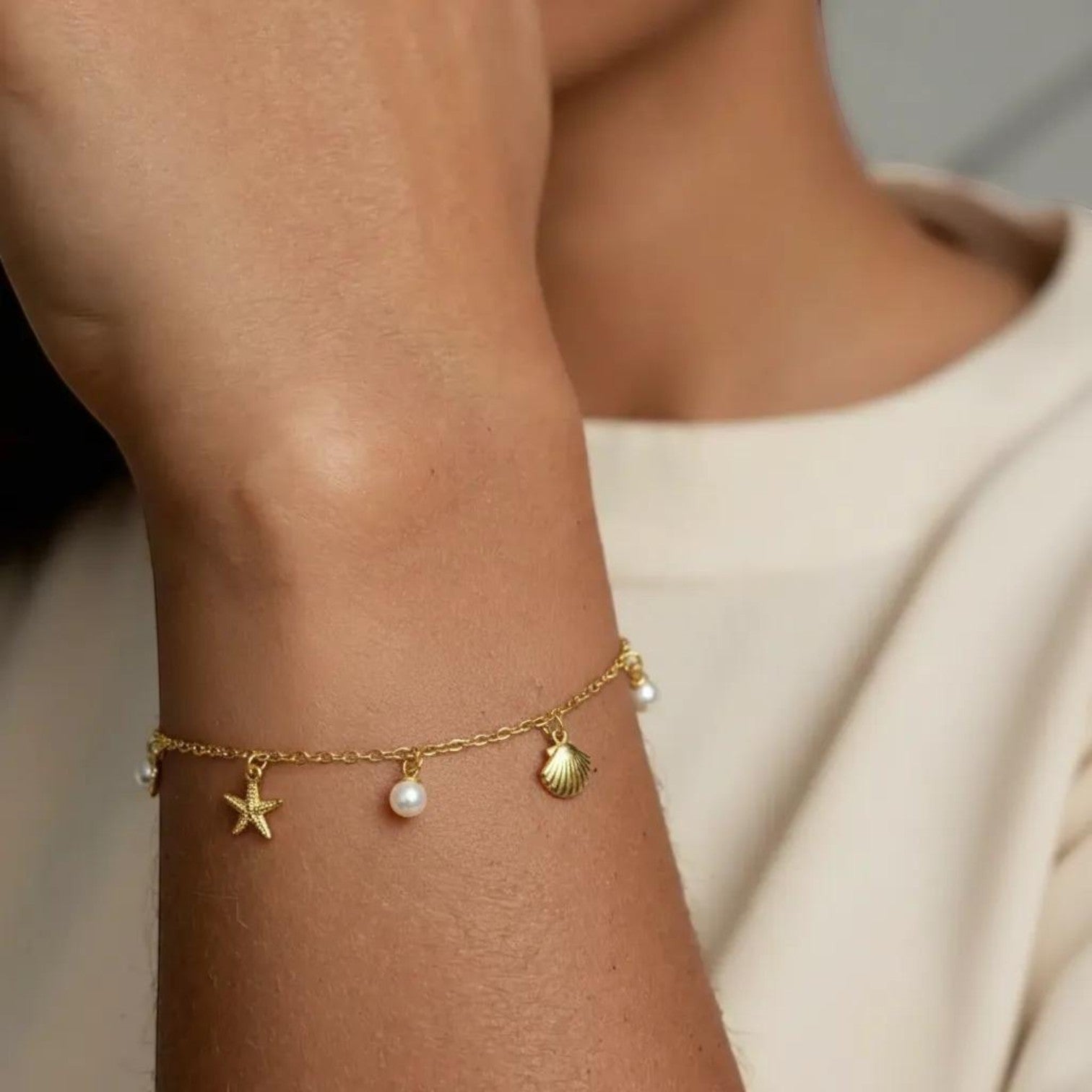 Amara Jewels gold-plated sterling silver bracelet with starfish, shell, and pearl charms.