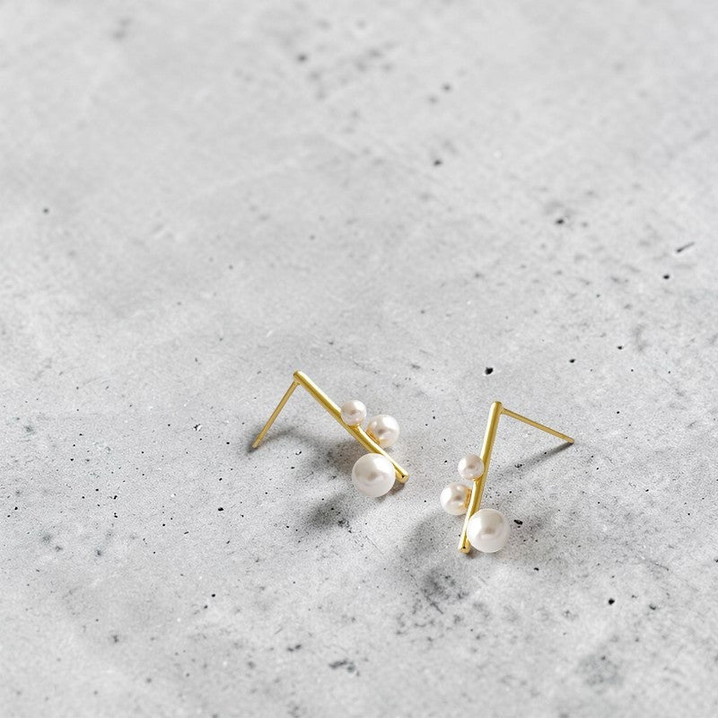 Amara Jewels gold plated sterling silver earrings with three pearls in varying sizes on a geometric bar.