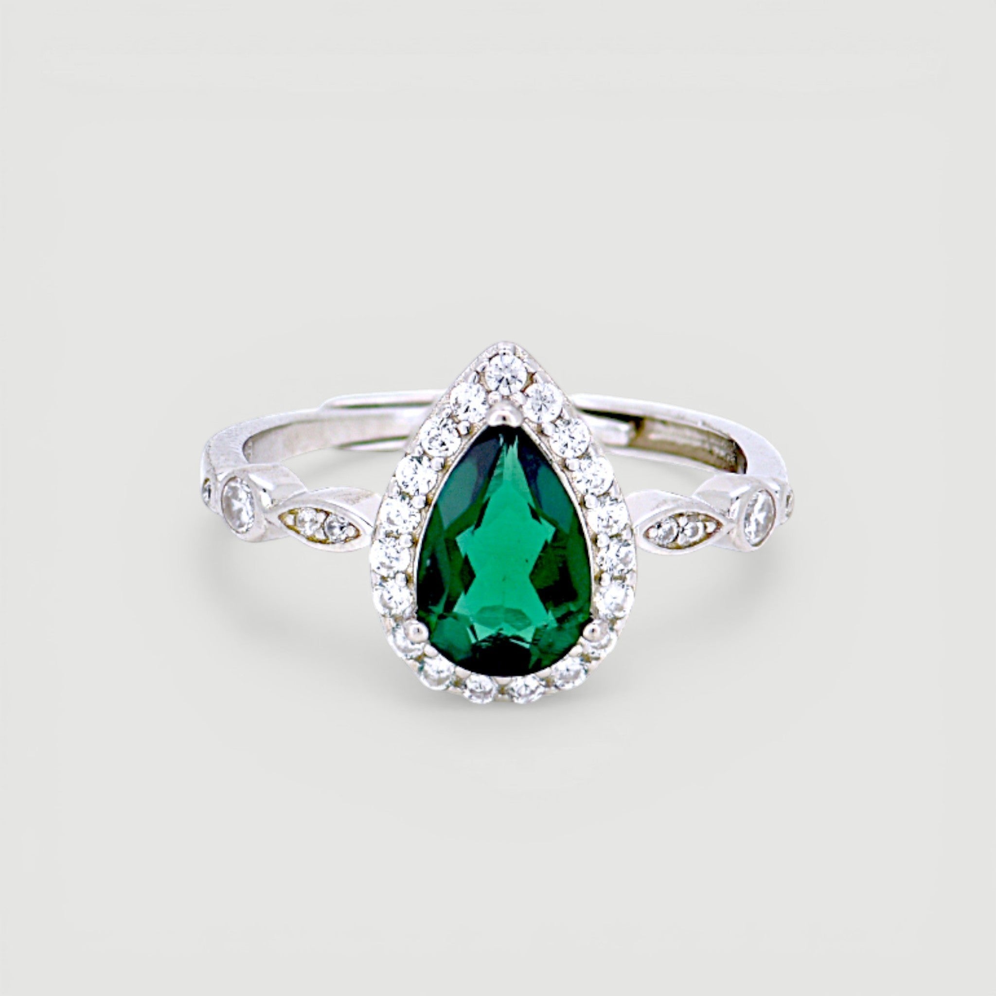 Amara Jewels sterling silver ring with a green teardrop gemstone surrounded by small clear stones. Intricate detailing on band.