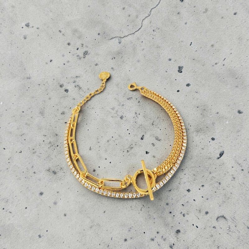 Amara Jewels layered gold bracelet with rhinestone, cable, and intricate chains, featuring a toggle clasp.