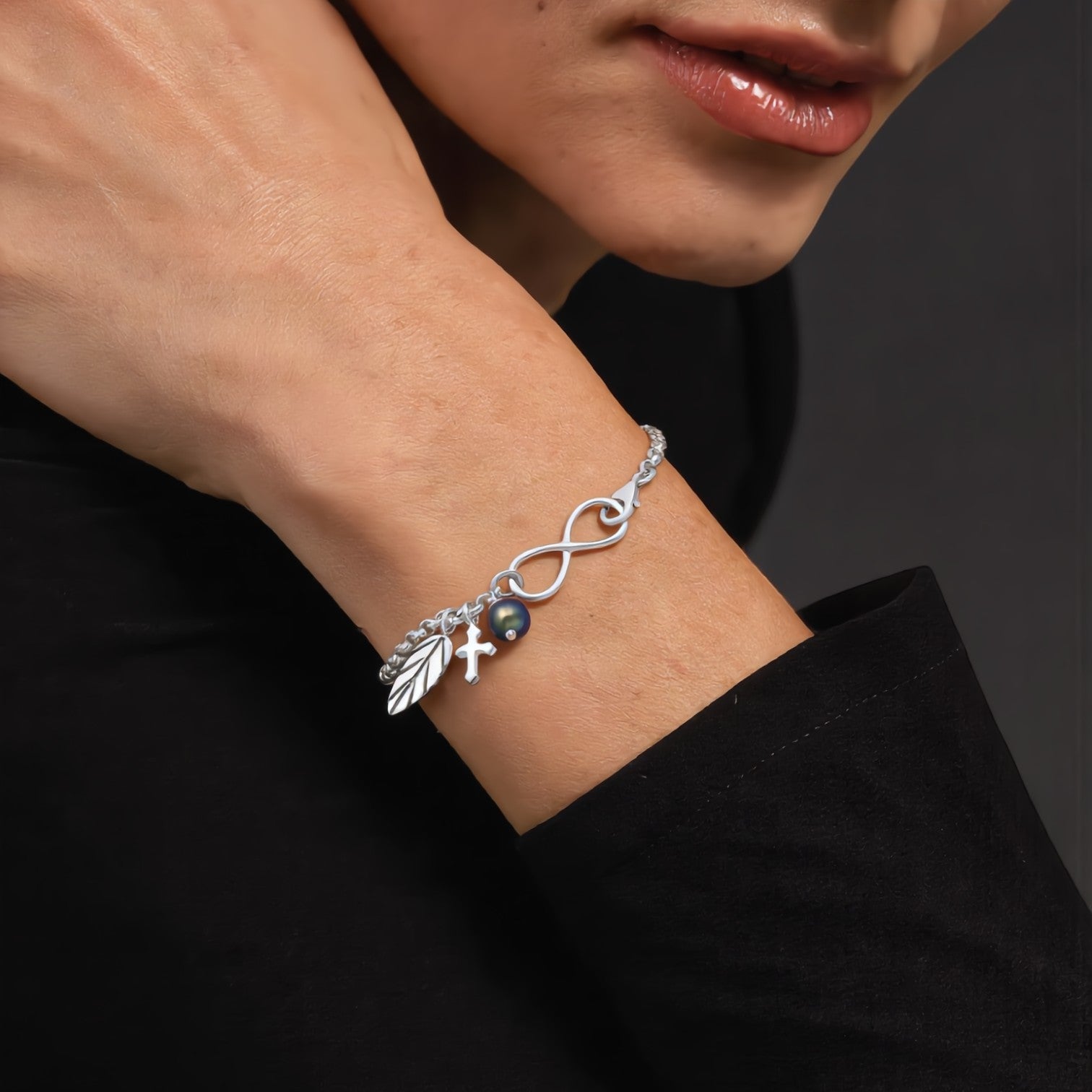 Amara Jewels sterling silver bracelet with infinity symbol, leaf charm, cross charm, and black pearl.