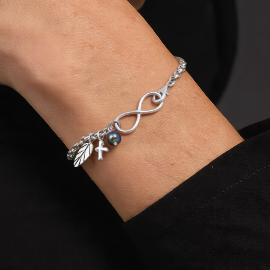 Amara Jewels sterling silver bracelet with infinity symbol, leaf charm, cross charm, and black pearl.