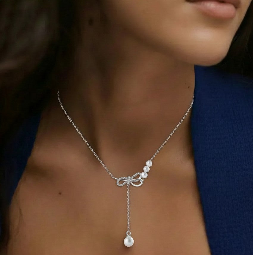 Amara Jewels sterling silver necklace with cubic zirconia bow and trio of white pearls and dangling single pearl drop.