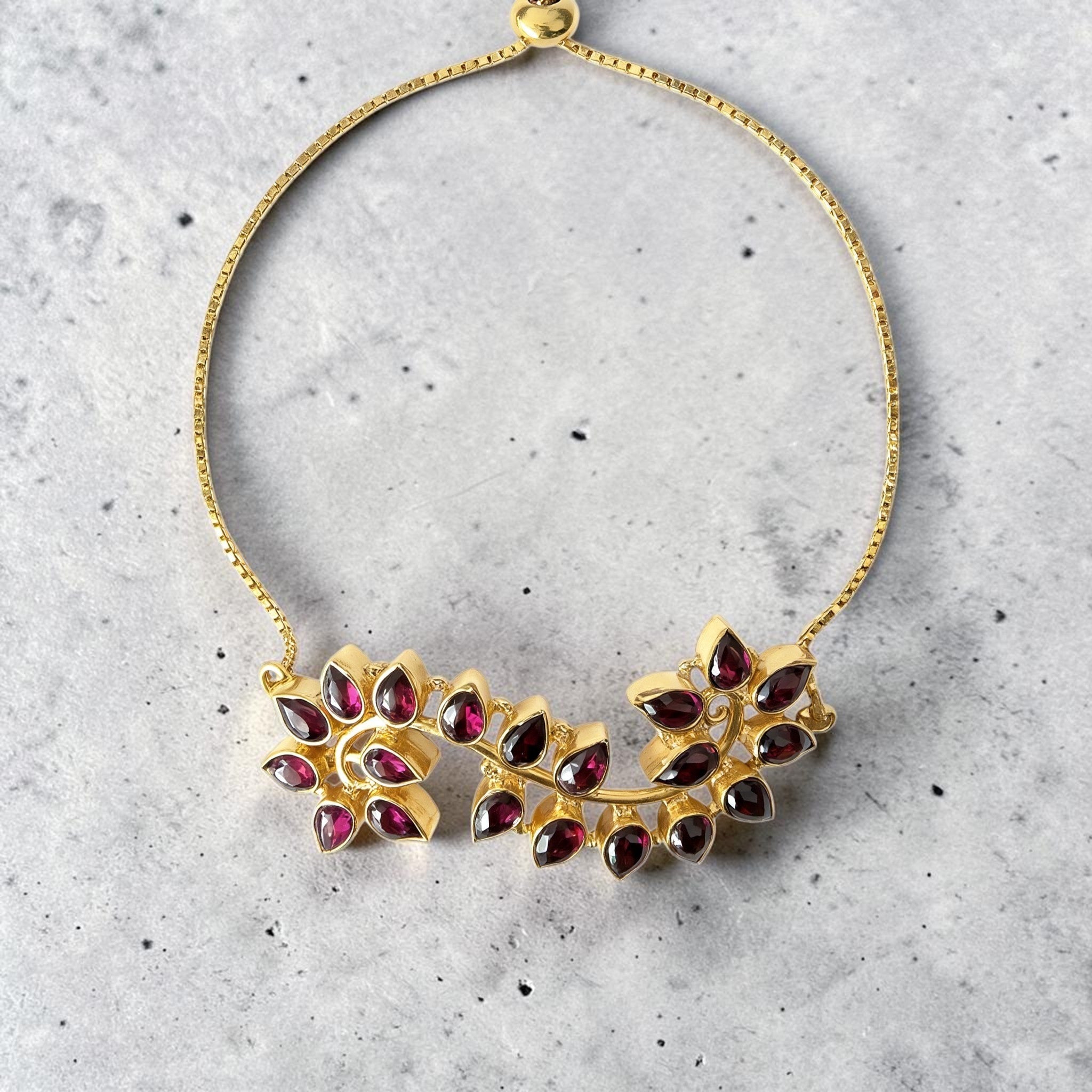 Amara Jewels Radiant Bloom Garnet Bracelet in gold vermeil, featuring pear-cut garnet stones in a floral vine design with adjustable slider.
