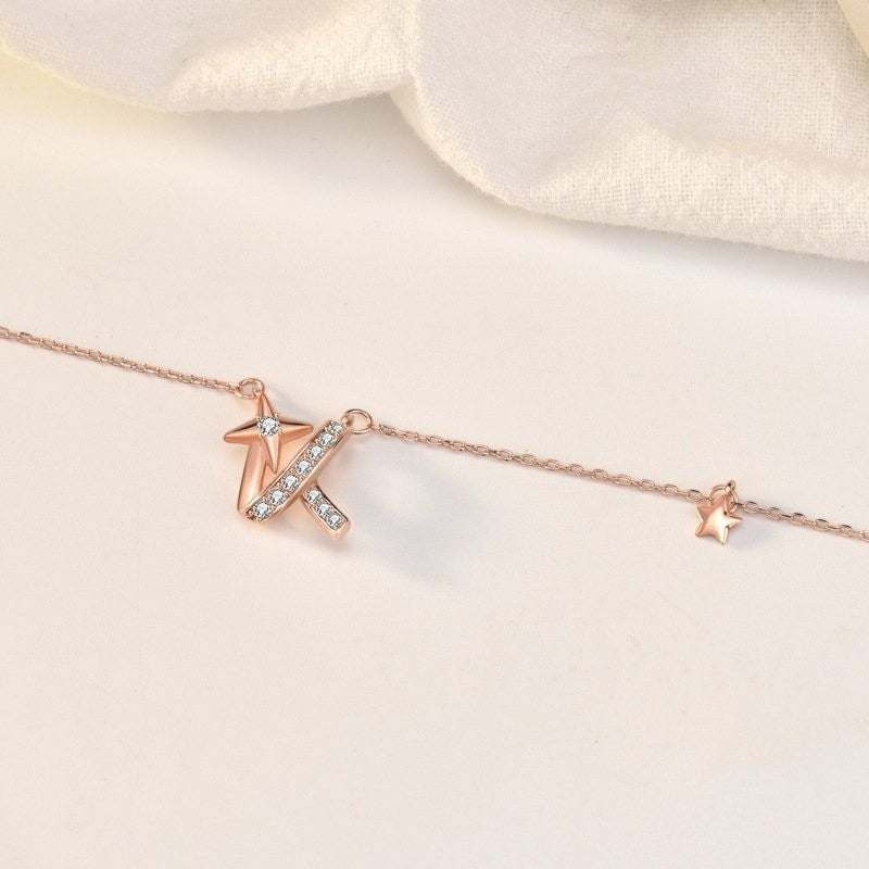 Amara Jewels rose gold necklace with a shooting star charm adorned with a diamond and a curved ribbon embellished with small diamonds.