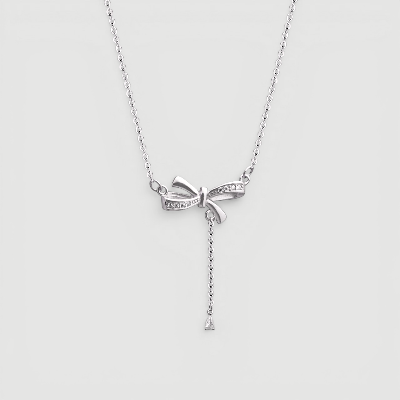 Amara Jewels sterling silver bow pendant necklace with cubic zirconia accents and a dangling pear-shaped stone.
