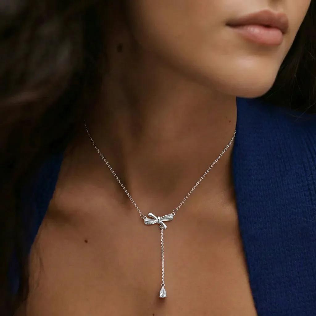 Amara Jewels sterling silver bow pendant necklace with cubic zirconia accents and a dangling pear-shaped stone.