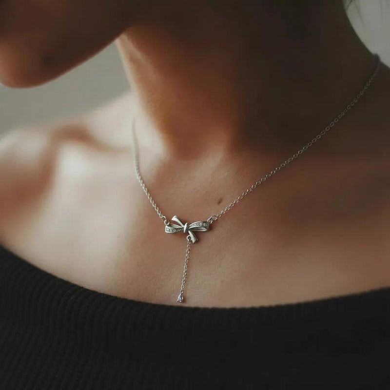 Amara Jewels sterling silver bow pendant necklace with cubic zirconia accents and a dangling pear-shaped stone.