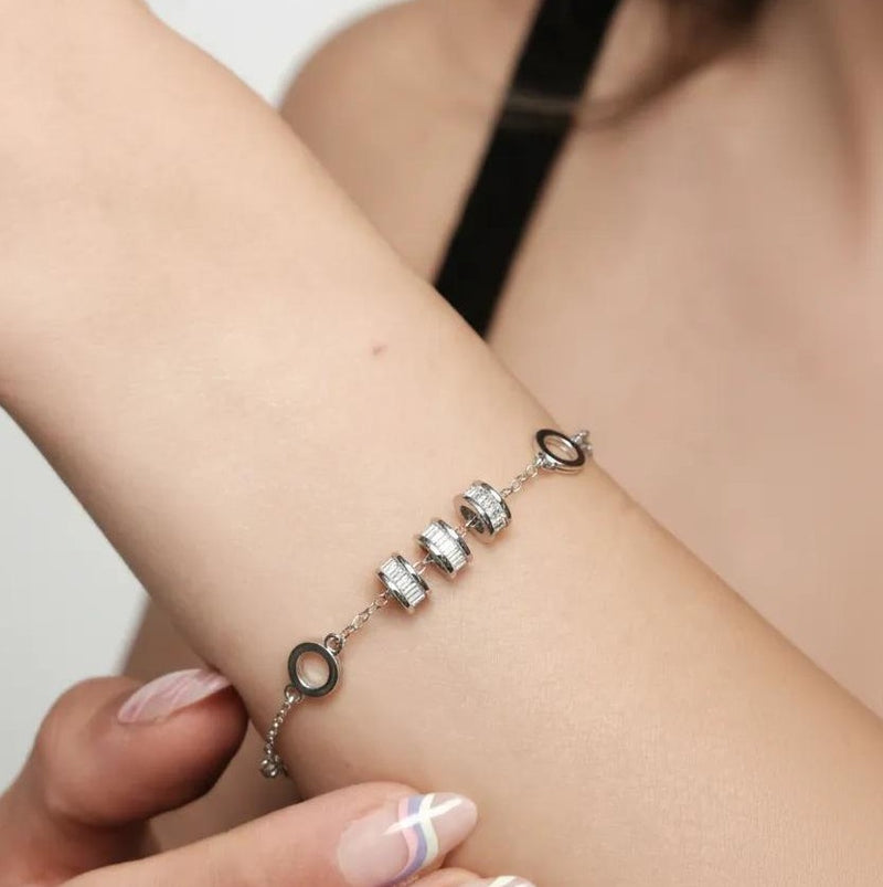 Amara Jewels 925 sterling silver bracelet with geometric charms and adjustable chain. Features circular and bar charms with baguette-cut stones.