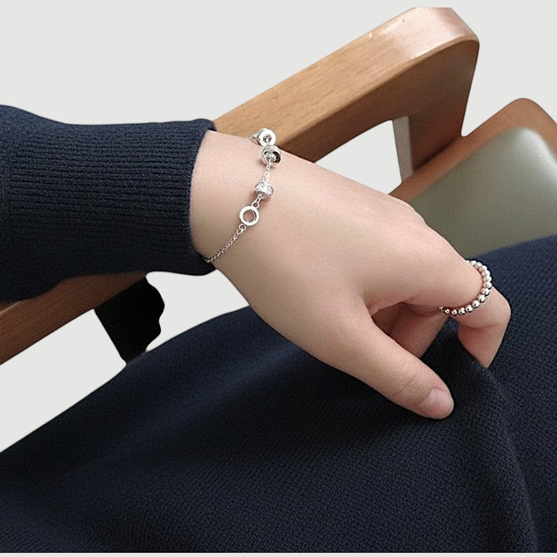 Amara Jewels 925 sterling silver bracelet with geometric charms and adjustable chain. Features circular and bar charms with baguette-cut stones.