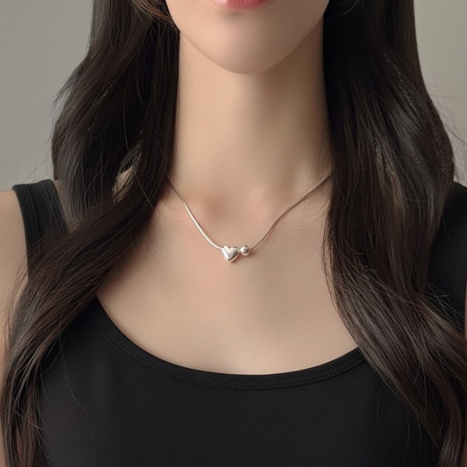 Amara Jewels sterling silver necklace with a heart charm and a small sphere.