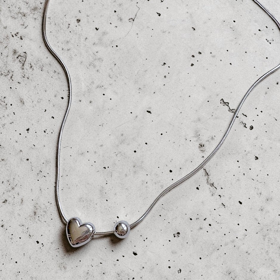 Amara Jewels sterling silver necklace with a heart charm and a small sphere.